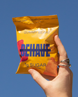 Hand holding a bag of 'Behave'  Sweet Gummy Bears against a blue sky.
