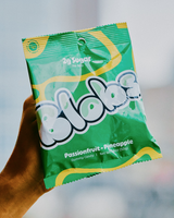 A package of Blobs low sugar Passionfruit Pineapple Gummies held against a blurry background.