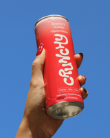 Hand holding a can of Crunchy Hydration Raspberry Stabilize against a blue sky.