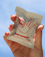 Hand holding a package of Hey Champ's Pretzel Candy Bar against an open sky.