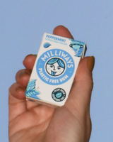 Hand holding a box of Milliways Peppermint Plastic Free Gum against a blue sky.