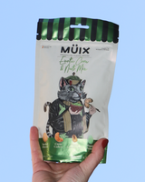 Hand holding a package of Muix Exotic Corn & Nuts mix against an open sky.