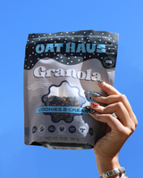 Hand holding Oat Haus - Cookies & Cream Granola on blue background