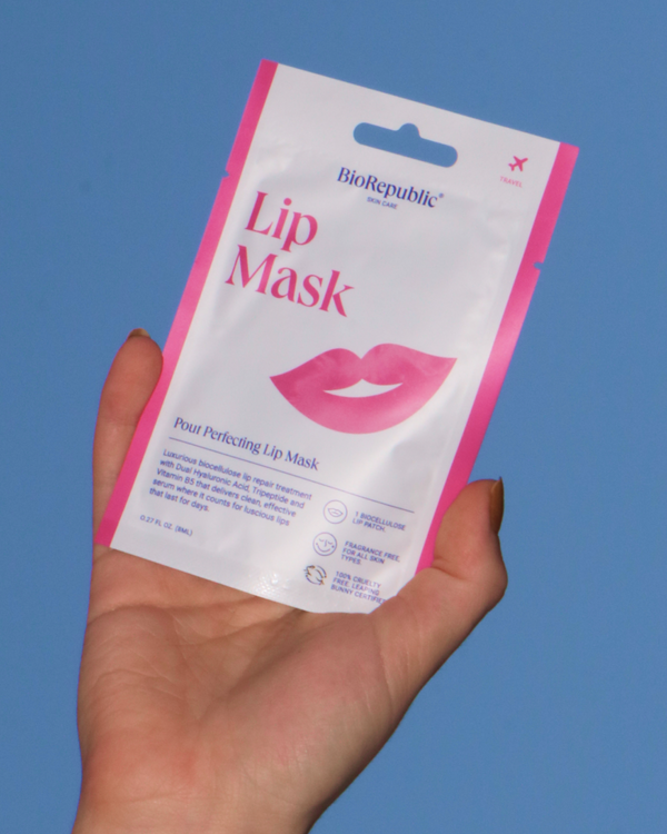 Hand holding a BioRepublic lip mask package against a blue sky.