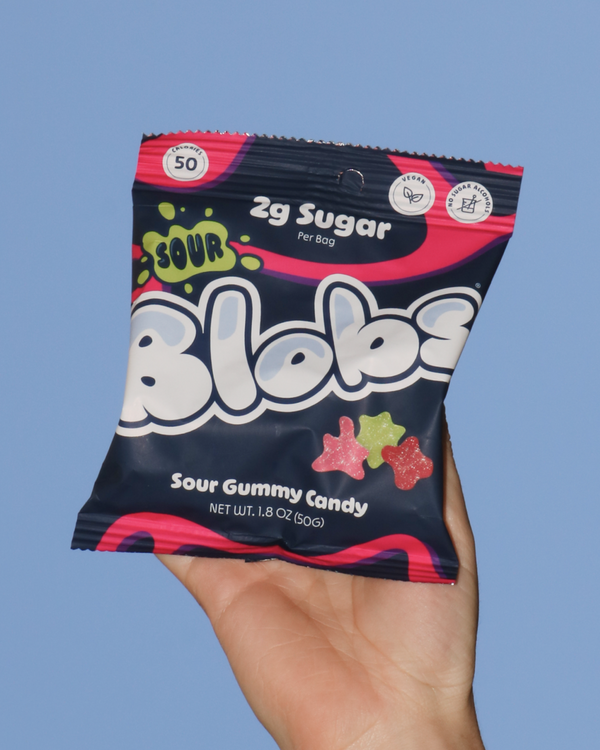 Hand holding a package of Blobs Sour Gummy Candy against a blue sky. 