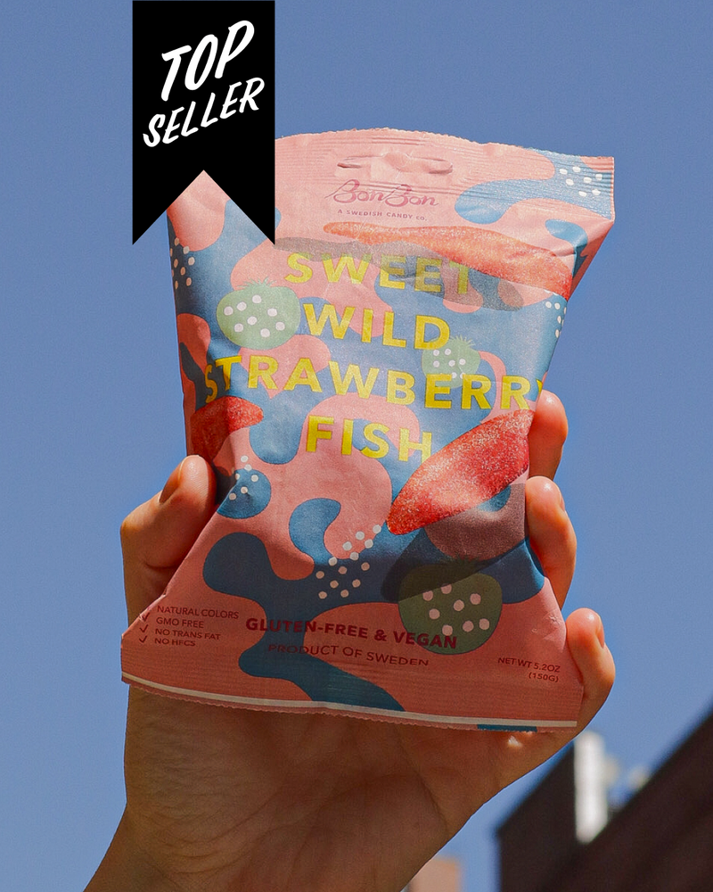 Hand holding a package of Bon Bon's 'Sweet Wild Strawberry Fish' with a blue sky background and a 'Top Seller' banner.