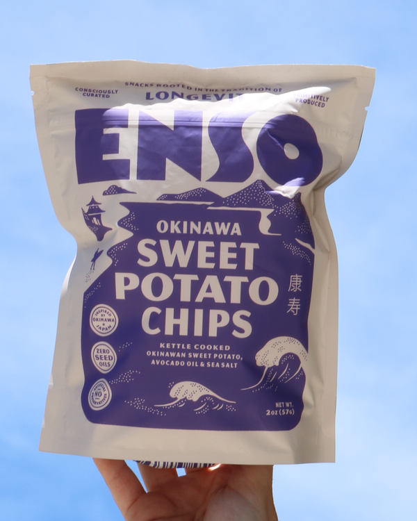 Enso Okinawa Sweet Potato Chips held against a blue sky.