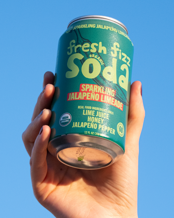 Hand holding a can of Fresh Fizz Sparkling Jalapeño Limeade against an open sky. 