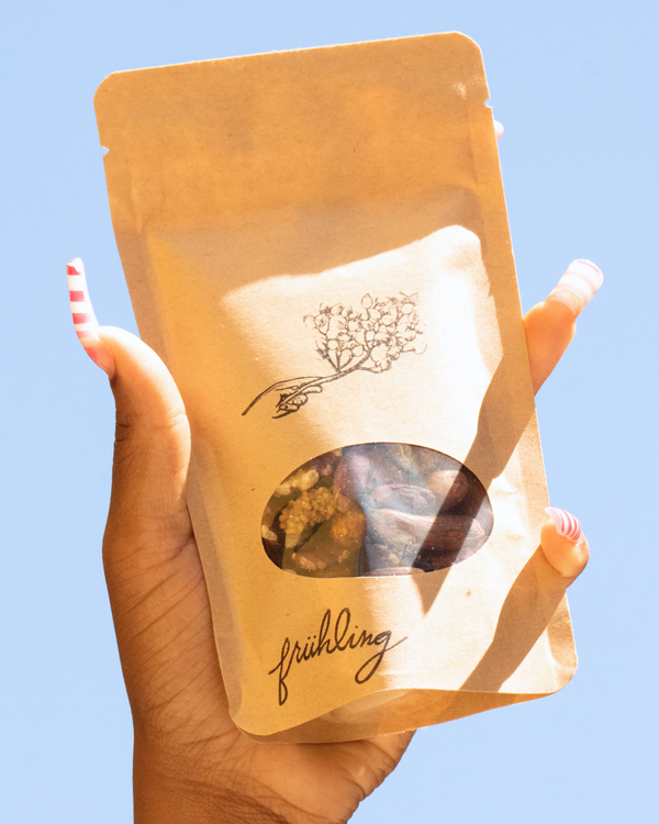 Hand holding a bag of Fruhling Superfood Snack against an open sky. 
