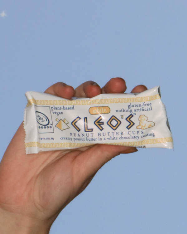 Hand holding a package of Go Max Go's Cleo's White Chocolate Peanut Butter Cups.