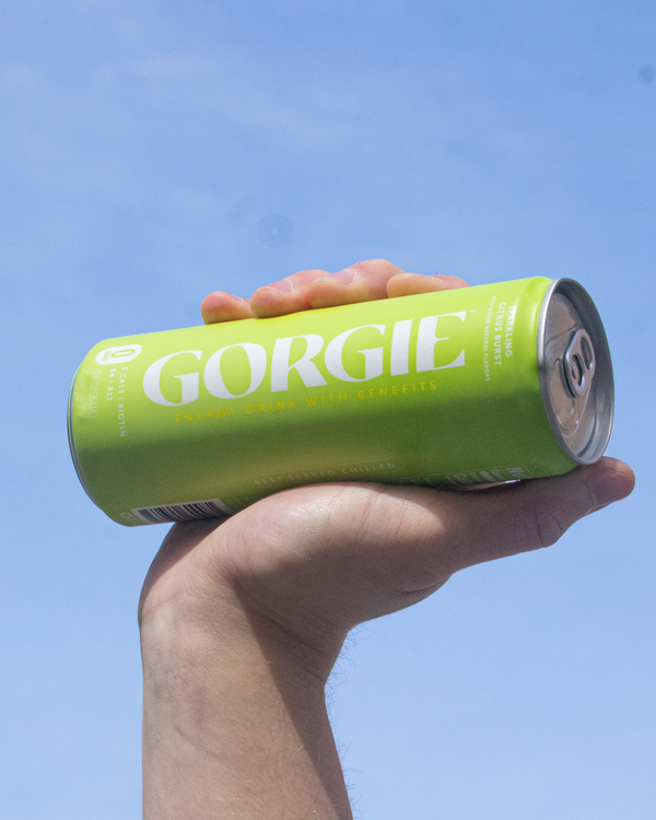 Hand holding a can of Gorgie Citrust Burst Sparkling Energy Drink against an open sky.