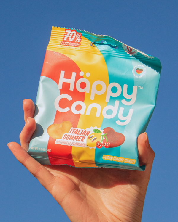 Hand holding a package of Happy Candy's Italian Summer flavor blend of gummies against an open sky.