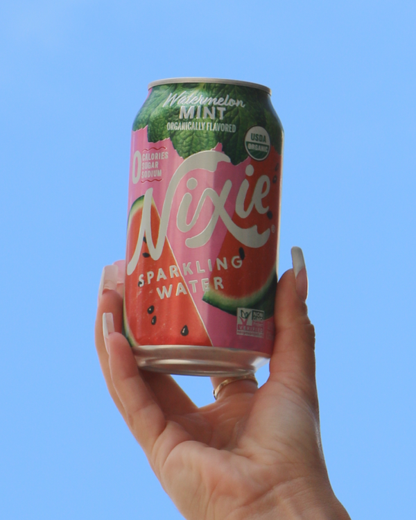Hand holding Nixie Watermelon Mint Sparkling Water on blue sky